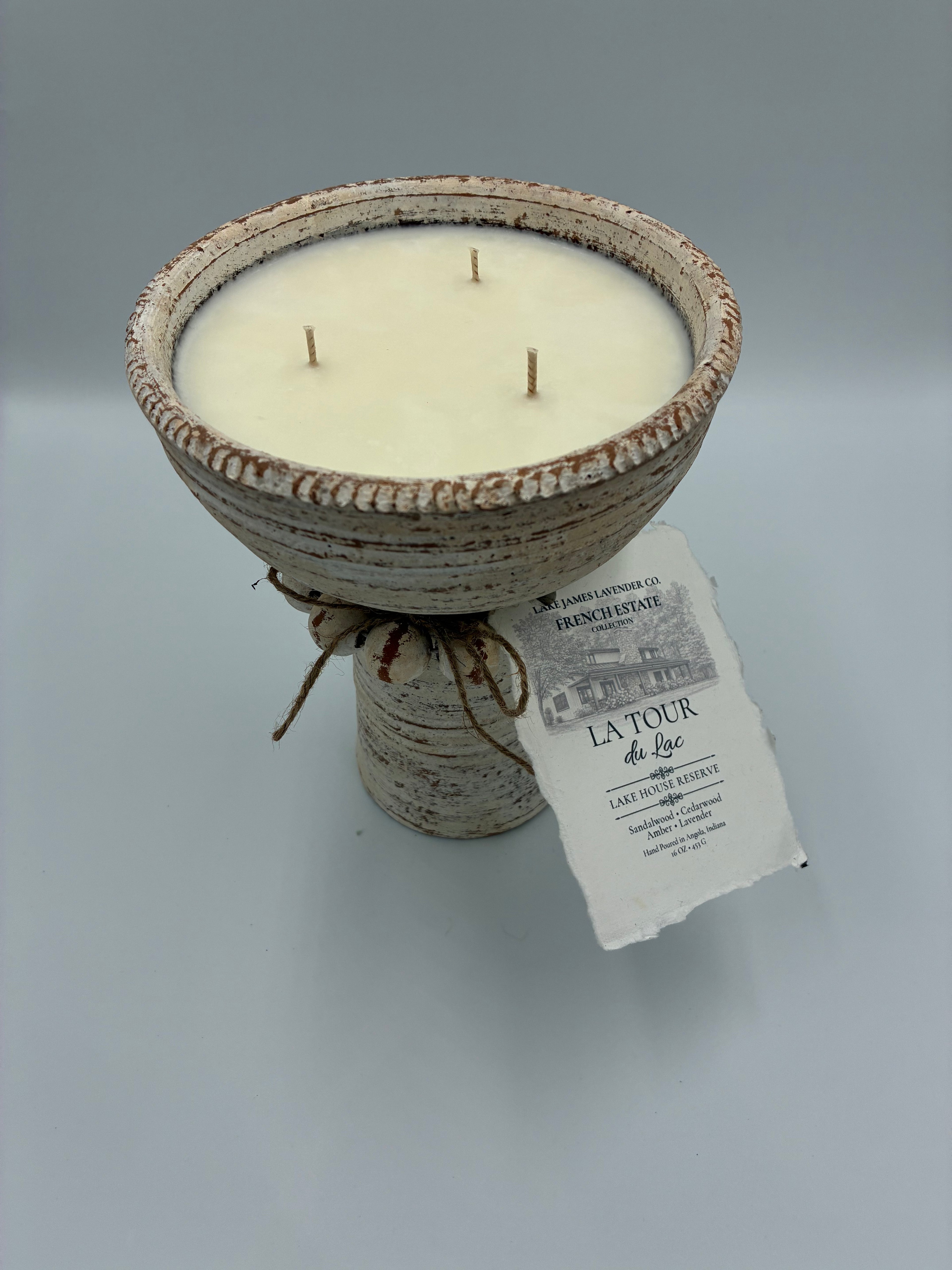 Ceramic candle holder with three wicks and a label on a gray background