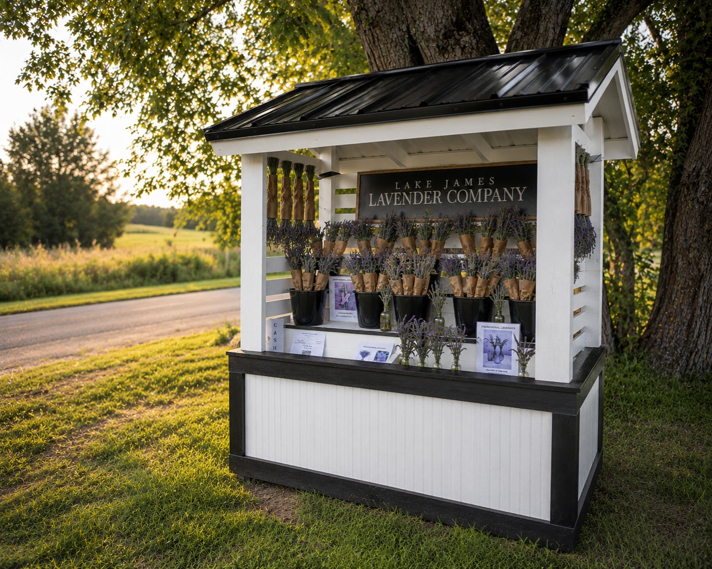Small white kiosk with black roof displaying lavender products in a natural setting.